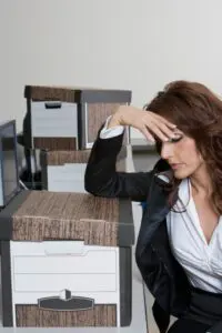 Business woman with moving boxes looking frustrated with her office move.