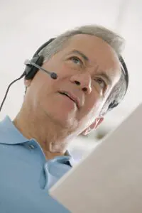 Man Using a Telephone Headset looking at his phone bill.