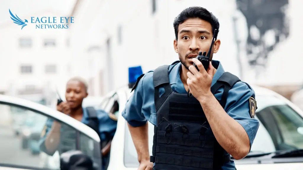 Police officer speaking on walkie talkie to 911 operators regarding live video footage provided by Eagle Eye Network's 911 Camera Sharing feature.