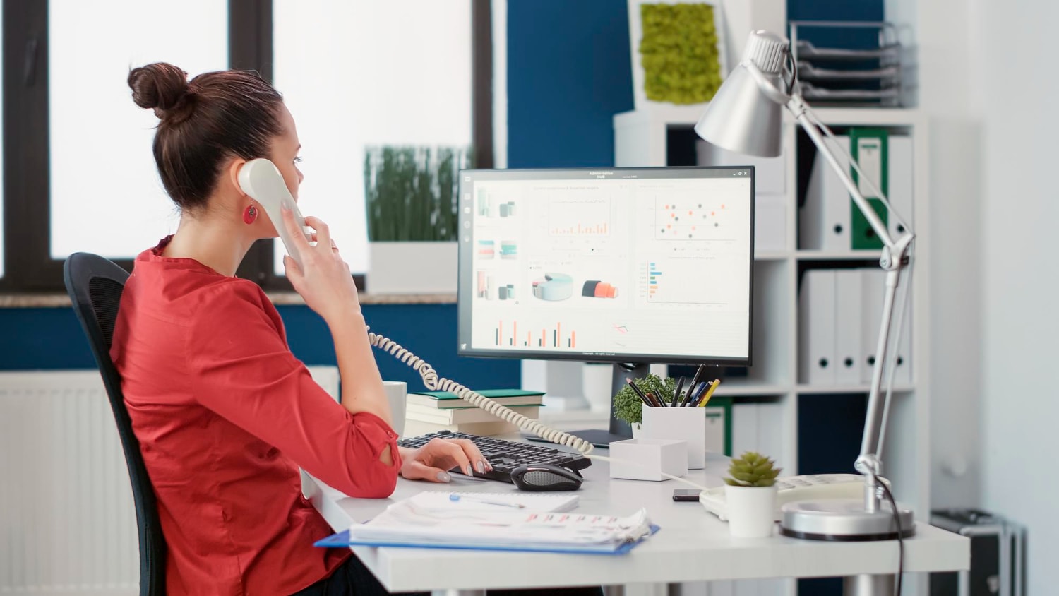 A person looking at their computer on the phone monitoring her Call Management system